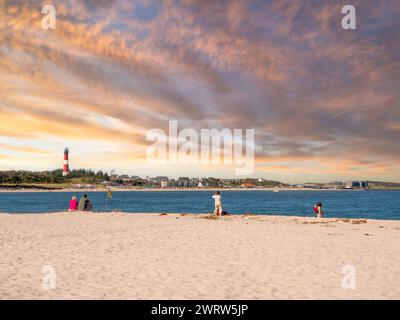 Les gens apprécient la côte de Hoernum avec phare au coucher du soleil, île de Sylt, Frise du Nord, Schleswig-Holstein, Allemagne Banque D'Images