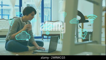 Image des icônes de cloud et wifi et du traitement des données sur une femme caucasienne utilisant un ordinateur portable Banque D'Images
