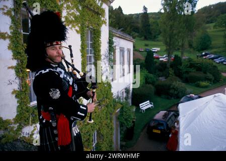 West Bagborough, Somerset, Angleterre 9 mai 1997. Le ballon de chasse annuel, un Piper écossais, se tient sur le balcon d'une pièce à l'étage et conduit les invités dans la chapiteau pour le dîner. 1990S UK HOMER SYKES Banque D'Images