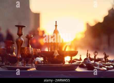 Vieux pot traditionnel en bronze et tasses souvenirs au marché de rue au coucher du soleil luisant à Boukhara Ouzbékistan. Voyage sur la route de la soie en Asie centrale. Banque D'Images