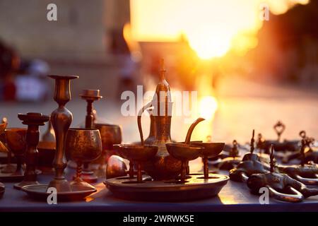 Vieux pot traditionnel en bronze et tasses souvenirs au marché de rue au coucher du soleil luisant à Boukhara Ouzbékistan. Voyage sur la route de la soie en Asie centrale. Banque D'Images