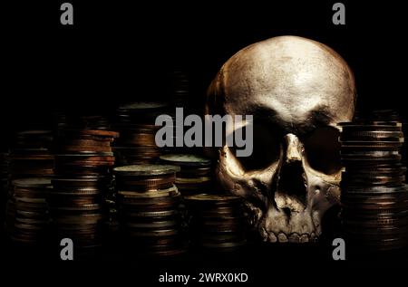 Photo d'un crâne humain ombragé posé au milieu d'une pile de pièces de monnaie. Banque D'Images