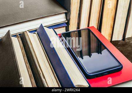 Photo de vieux livres anciens posés sur la surface de la table en cuir avec smartphone. Banque D'Images