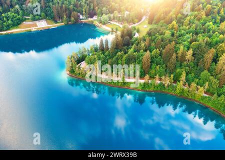 Vue aérienne de la route près du lac bleu, forêt verte au lever du soleil Banque D'Images