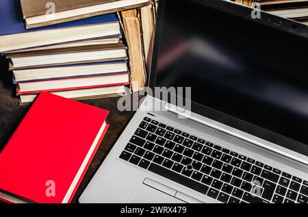 Photo d'ordinateur portable moderne ou cahier posé sur la table avec de vieux livres anciens. Banque D'Images