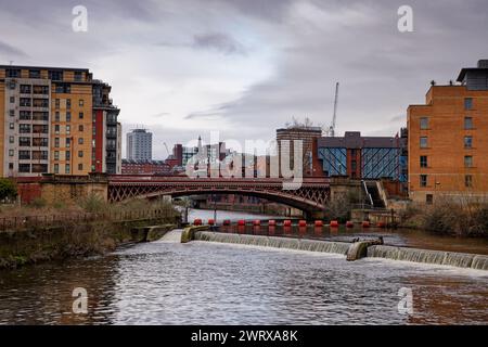 Une rivière urbaine qui coule à travers un centre-ville sous un pont et au-dessus d'un déversoir, River aire à Leeds, Yorkshire. Banque D'Images