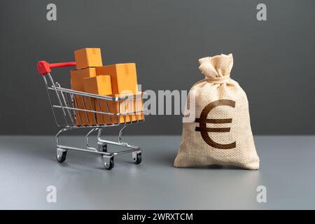 Panier avec boîtes de marchandises et sac d'argent en euros. Pouvoir d'achat des acheteurs. Commerce et détail. Impôts et revenus. Prix à la consommation. Importation de produ Banque D'Images