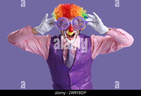 Portrait de clown avec des verres de nouveauté sur fond lilas. Fête du fou d'avril Banque D'Images
