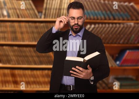 Avocat confiant dans des lunettes lisant le livre au bureau Banque D'Images