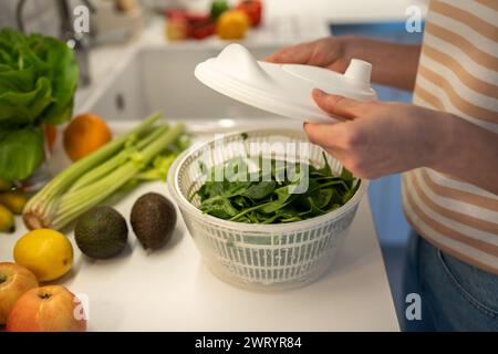 Cuisson d'un dîner sain frais rapide en préparant des épinards verts, du céleri dans un sèche-linge en plastique à la main. Banque D'Images