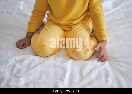Enfant assis W posture sur le lit Banque D'Images