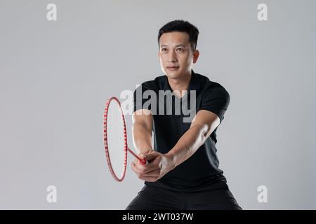 Joueur de badminton portant des vêtements de sport debout tenant une raquette dans le fond blanc. Banque D'Images