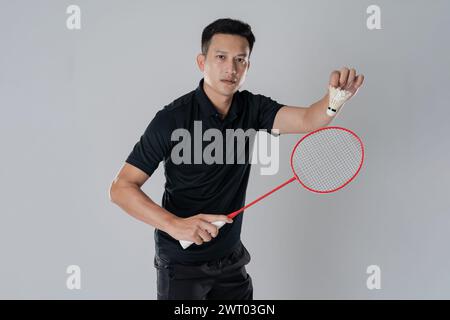 Joueur de badminton portant des vêtements de sport debout tenant une raquette dans le fond blanc. Banque D'Images