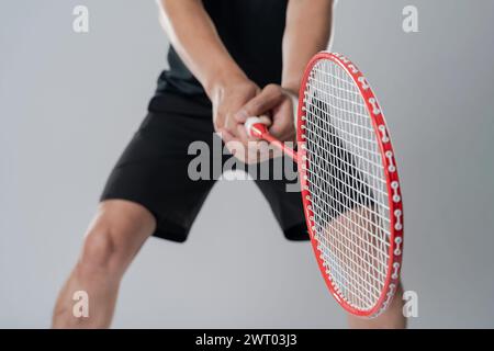 Joueur de badminton portant des vêtements de sport debout tenant une raquette dans le fond blanc. Banque D'Images