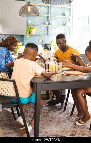 Une famille afro-américaine disant grâce et priant avant le petit déjeuner ensemble à la maison Banque D'Images