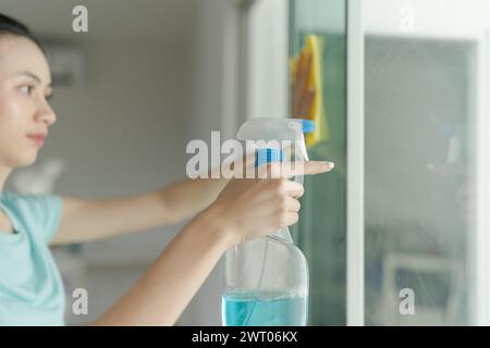 Belle femme nettoyant le miroir de la maison. Banque D'Images