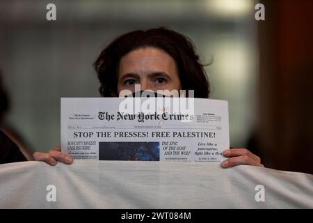 New York, États-Unis. 14 mars 2024. Un manifestant pro-palestinien tient un faux numéro d'un journal qui lit, "les crimes de guerre de New York", dans le hall des bureaux du New York Times lors d'une action critiquant la couverture par le journal de la guerre Israël-Hamas le 14 mars 2024 à New York. Les manifestants ont bloqué les entrées de sécurité pendant près de deux heures, ce qui a entraîné environ 100 arrestations. (Photo de Michael Nigro/Pacific Press) crédit : Pacific Press Media production Corp./Alamy Live News Banque D'Images