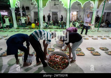 Des bénévoles distribuent et organisent des rangées de repas 'iftar' pour les dévots afin de rompre leur jeûne, pendant le mois sacré du Ramadan, à Burha Jame Masjid, on Banque D'Images