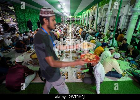 Des bénévoles distribuent et organisent des rangées de repas 'iftar' pour les dévots afin de rompre leur jeûne, pendant le mois sacré du Ramadan, à Burha Jame Masjid, on Banque D'Images