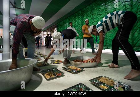 Des bénévoles distribuent et organisent des rangées de repas 'iftar' pour les dévots afin de rompre leur jeûne, pendant le mois sacré du Ramadan, à Burha Jame Masjid, on Banque D'Images