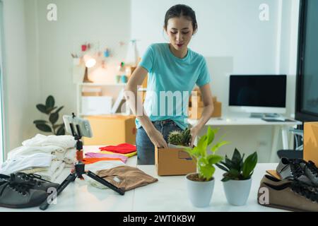 Belle jeune femme travaillant à la boutique en ligne portant des vêtements décontractés, elle vérifie l'adresse de l'ordinateur portable du client et les informations sur le produit elle possède un smal Banque D'Images