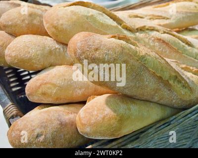 Baguettes complètes fraîchement biologiques dans un panier à pain tressé. Banque D'Images