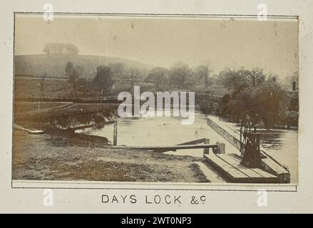 Jours de verrouillage &c. Henry W. Tunt, photographe (britannique, 1842 - 1922) 1897 une des deux photographies illustrant une carte imprimée de Little Wittenham, Dorchester, Warborough et les environs le long de la Tamise. La photographie montre une vue d'un pont derrière l'écluse des jours depuis le sud. Une partie de la structure de l'écluse est visible au premier plan, et une parcelle d'arbres au sommet de Round Hill, connue sous le nom de touffes de Wittenham, peut être vue au loin. (Recto, monture) centre inférieur, ci-dessous image, imprimé à l'encre noire : 'DAYS LOCK &c.' Banque D'Images