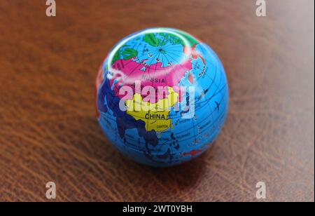 Petit globe rond avec Une image visible des pays asiatiques reposant sur la surface en cuir Banque D'Images