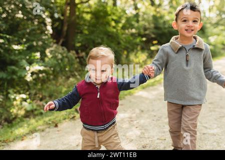 Deux enfants heureux sur une promenade ensemble sur un chemin forestier se tenant la main Banque D'Images