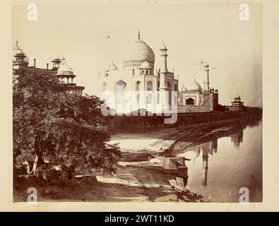 Taj Mahal depuis les rives de la rivière Yamuna. John Edward Saché, photographe (prussien ou britannique, né en Prusse, 1824 - 1882) années 1850–1890 vue du Taj Mahal et de la rivière Yamuna depuis la rive juste à l'est du célèbre mausolée. Deux personnages peuvent être vus laver des vêtements et les déposer pour les sécher sur la rive juste à côté d'un ghat, un court ensemble de marches de pierre menant à l'eau, au premier plan. Les dômes du Mihman Khana sont visibles au-dessus des arbres sur le côté gauche de l'image. Banque D'Images