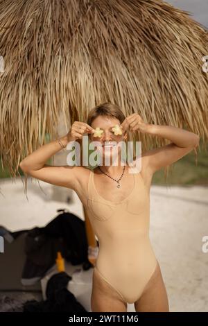 Jeune femme tropicale tenant des fruits de carambola pour ses yeux. Banque D'Images