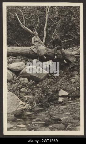 Figurines assises sur un arbre tombé au-dessus du ruisseau. Louis Fleckenstein, photographe (américain, 1866 - 1943) 1907-1943 Banque D'Images