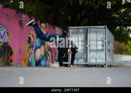 Jeune danseur de hip-hop asiatique pratiquant la danse, effectuant des mouvements freestyle dans la rue de la ville Banque D'Images