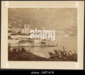 Monte Carlo, le tir aux pigeons. G. J., photographe (français, actif années 1870 - années 1880) 1870–1880 vue du Casino de Monte Carlo et des collines qui l'entourent depuis l'autre côté de l'eau. Le casino est vu de côté à un angle et il y a du feuillage au premier plan. Banque D'Images