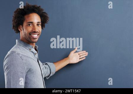 Portrait, sourire ou homme avec la main pointant vers la maquette en studio pour les nouvelles, l'offre ou l'info giveaway sur fond gris. Spectacle mannequin heureux, visage ou homme Banque D'Images