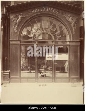 Vieille Empire, 21 faubourg Honoré (magasin d'antiquités, rue du Faubourg-Saint-Honoré). Eugène Atget, photographe (français, 1857 - 1927) 1902 L'étude d'Eugène Atget sur l'élégante façade de style Empire de cette devanture de la rue du Faubourg-Saint-Honoré ne capture qu'une phase de l'histoire architecturale d'un bâtiment construit à l'origine en 1776 comme une maison privée double. Cette section a été vendue en 1787 à un apothicaire, qui a probablement transformé la façade en magasin. Quand Atget a photographié la structure en 1902, les fenêtres originales avec de petites vitres avaient été remplacées par plat Banque D'Images