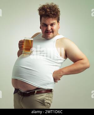 Obèse, gain de poids et lager pour homme en studio avec boisson pour habitude malsaine, plus taille et blague. Personne en surpoids avec verre sur l'estomac gras pour Banque D'Images