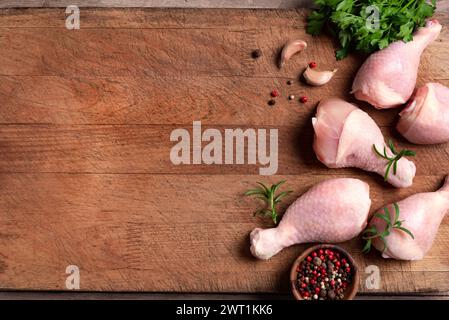 Cuisses de poulet avec épices, herbes et ail prêt pour la cuisson sur planche à découper, vue de dessus, espace de copie. Viande de poulet biologique crue. Banque D'Images
