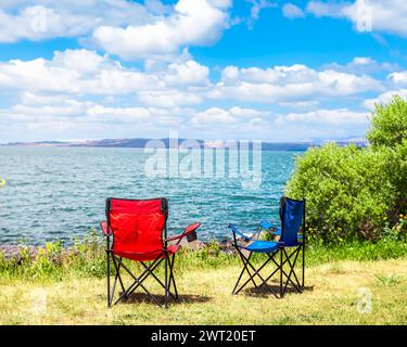 Scène estivale relaxante avec deux chaises vides face à un lac serein. Fond de vacances d'été. Ardahan, Turquie. Banque D'Images