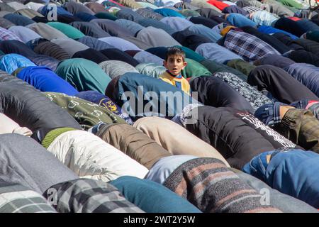 Srinagar, Inde. 15 mars 2024. Un garçon musulman cachemiri regarde les dévots offrir des prières devant la Jamia Masjid ou la Grande Mosquée le premier vendredi du Ramadan à Srinagar. Les musulmans du monde entier marquant le mois sacré du Ramadan en priant pendant la nuit et en s’abstenant de manger et de boire pendant la période entre le lever et le coucher du soleil. Le Ramadan est le neuvième mois du calendrier islamique et on pense que le premier verset du Coran a été révélé au cours de ses 10 dernières nuits. Crédit : SOPA images Limited/Alamy Live News Banque D'Images