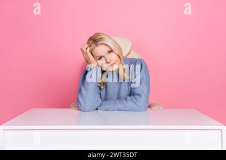 Photo de la femme déprimée stressée porter un pull assis bureau se sentant mal isolé fond de couleur rose Banque D'Images