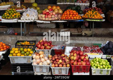 Une variété de fruits frais, y compris des pommes, des poires, des raisins, des fraises et des agrumes, dans des paniers en plastique sur un marché en plein air à Sapa, au nord du Vietnam Banque D'Images