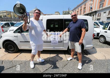 Deux chauffeurs de taxi pointent vers un dépliant de protestation sur la Piazza Plebiscito à Naples, occupée par plus de 500 taxis pour protester contre l'IT Banque D'Images