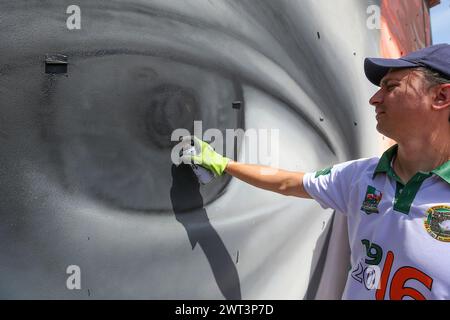 L'artiste Jorit alors qu'il peint l'œil de la murale représentant le célèbre chanteur-compositeur italien Fabrizio de Andrè, sur le mur d'un bâtiment en t Banque D'Images