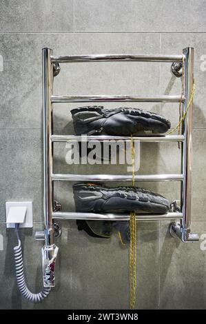 Chaussures de randonnée séchant après grand camping. Bottes noires pour la randonnée couchée sur sèche-linge dans la salle de bain. Banque D'Images