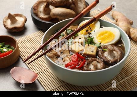 Bol de délicieux ramen et ingrédients sur la table grise. Soupe de nouilles Banque D'Images