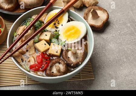 Bol de délicieux ramen et ingrédients sur la table grise. Soupe de nouilles Banque D'Images