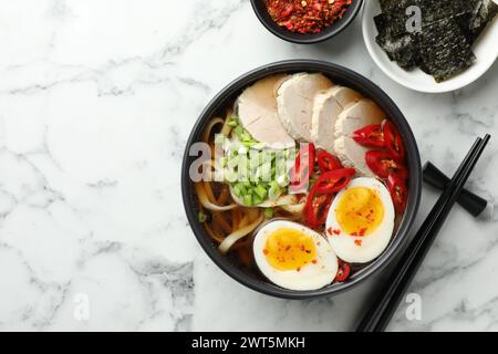 Délicieux ramen dans un bol servi sur une table en marbre blanc, plat avec espace pour le texte. Soupe de nouilles Banque D'Images