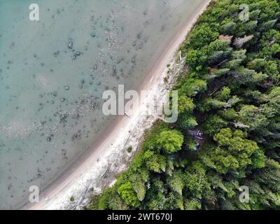 Vue de haut en bas de la plage isolée sur le lac supérieur avec une forêt de pins et camping dans une petite clairière Banque D'Images