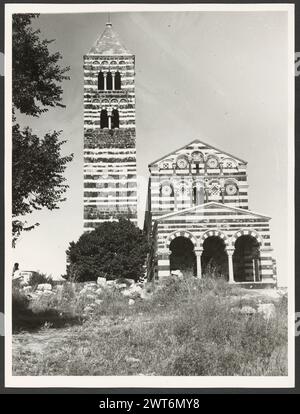 Sardaigne Sassari Sassari (environs) SS. Trinita di Saccargia (camaldolite). Hutzel, Max 1960-1990 les vues extérieures d'une église romane (XIIe siècle) comprennent : une façade rayée (basalte foncé et calcaire blanc) ; une tour d'influence pisane et Lucchésienne ; et des chapiteaux décorés / grotesques. Antiquités : deux colonnes et chapiteaux du portique. Notes de l'objet : Hutzel date de la campagne photo : 16 avril 1983 le photographe et chercheur d'origine allemande Max Hutzel (1911-1988) photographié en Italie du début des années 1960 jusqu'à sa mort. Le résultat de ce projet, appelé Foto Arte Minore par Hutzel, est thorou Banque D'Images